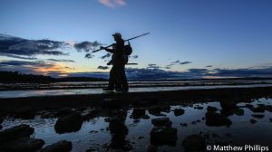 Two fishermen return from Cramond Island late on a summer's evening, Edinburgh.